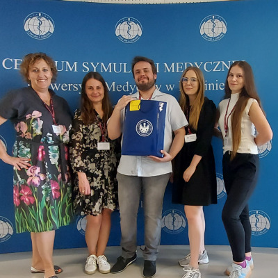 studenci z dyplomami w rękach na tłe ścianki reklamowej
